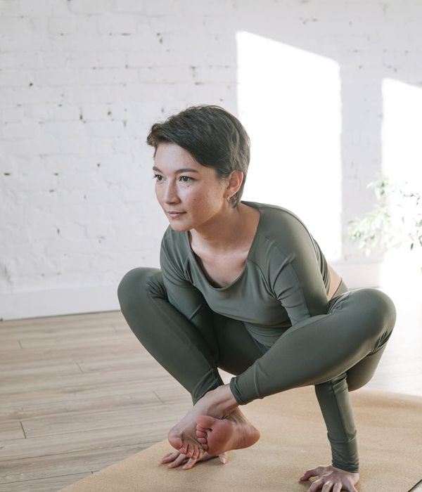Woman in a calm exercise pose in a bright, airy room.